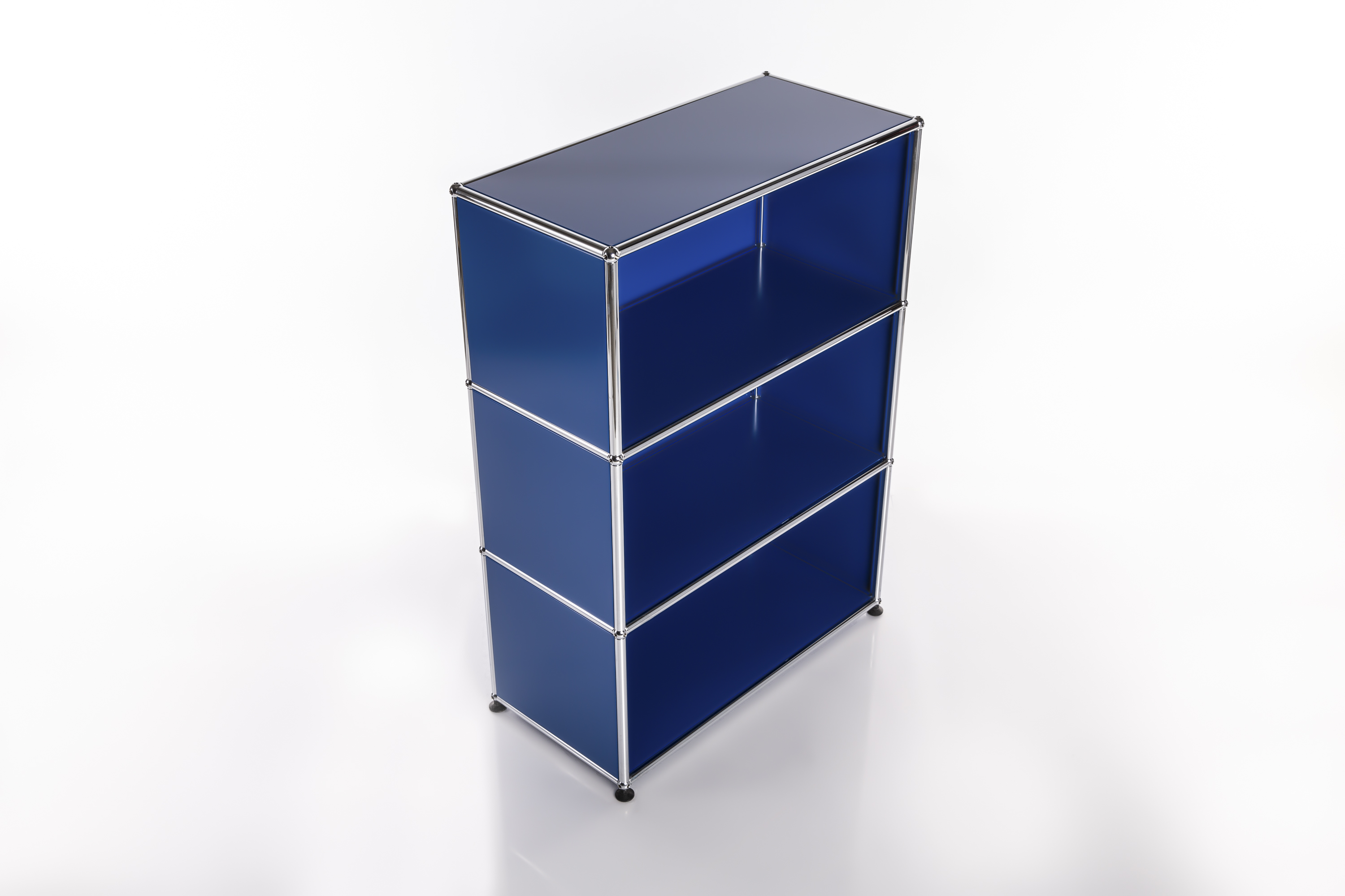 Moderna scaffalatura modulare a tre ripiani in brillante blu reale. Ripiani aperti, incorniciati da tubi cromati lucidi e giunti sferici. Su discreti piedini neri su uno sfondo bianco chiaro, con leggero effetto specchiato.