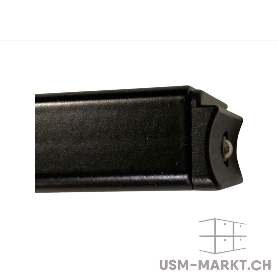 Nahaufnahme eines mattschwarzen, rechteckigen Profils mit feiner Textur. Das Ende des Profils ist mit einer abgerundeten, ebenfalls schwarzen Kappe versehen. Im Zentrum dieser Kappe ist ein kleiner, heller kugelförmiger Einsatz zu sehen, der hervorsteht.