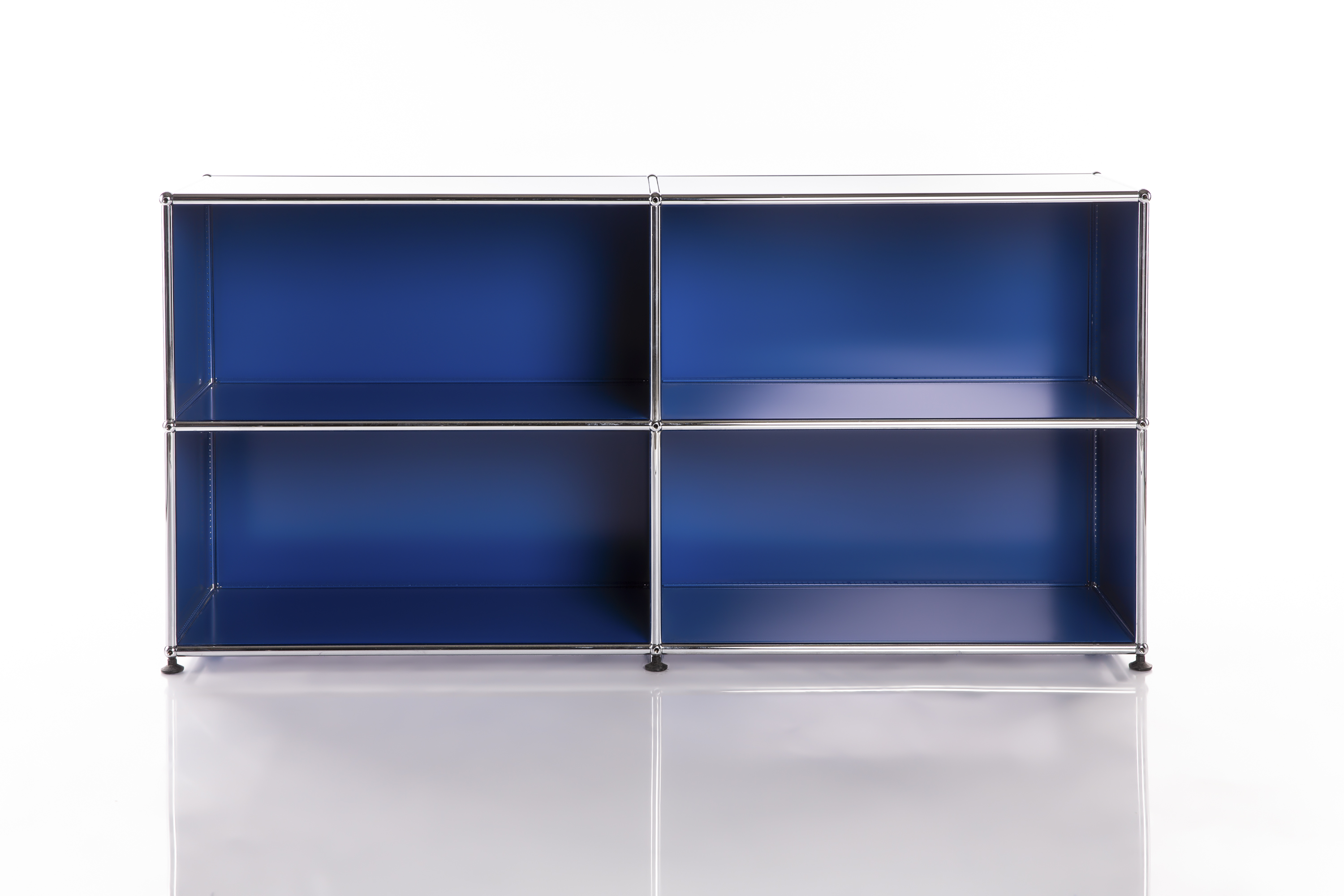Système d'étagères moderne et modulaire, de couleur bleu foncé, composé de quatre compartiments carrés. Structure en tubes métalliques chromés brillants et raccords. Sur un fond blanc réfléchissant, dans un style minimaliste.