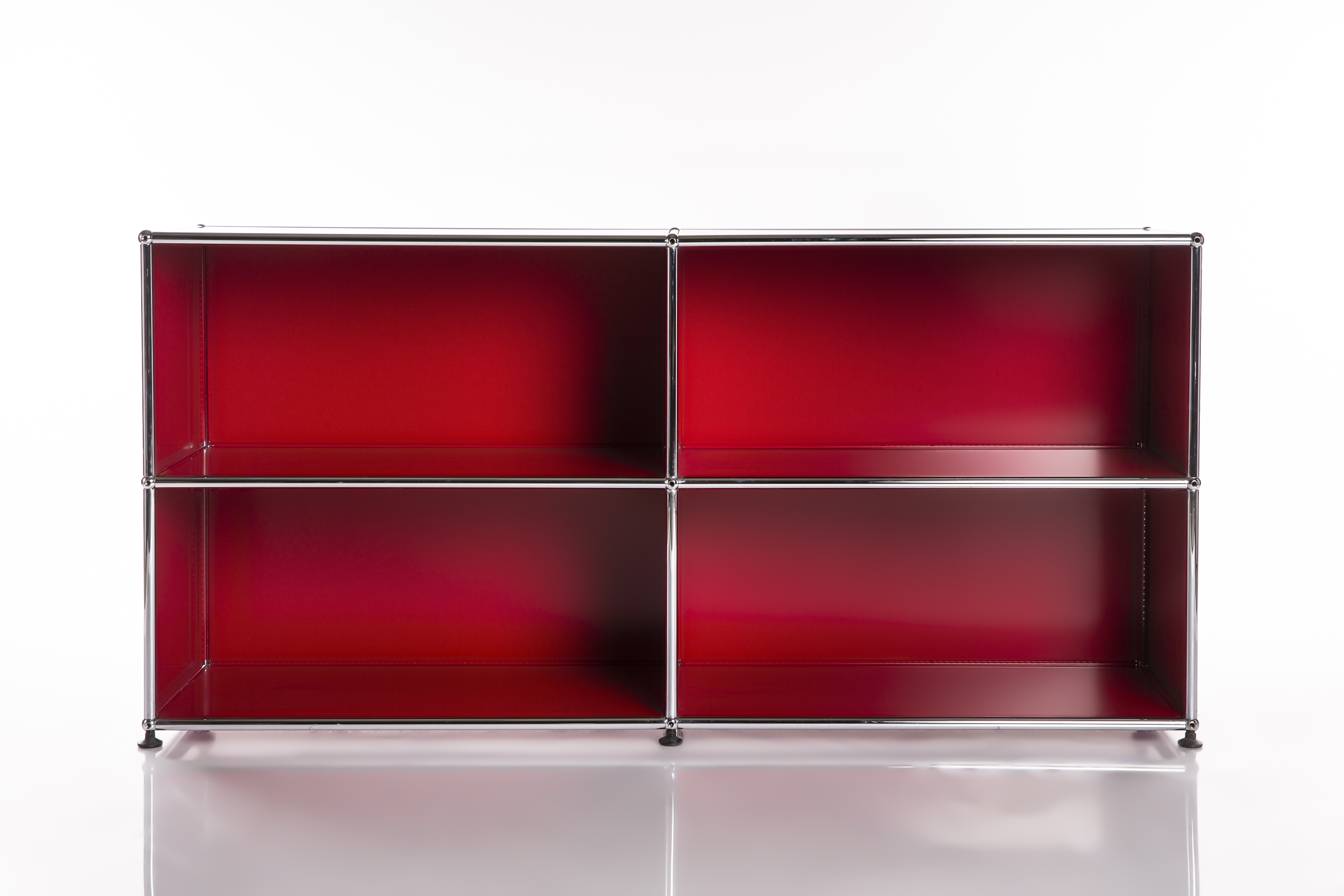 Moderna scaffalatura modulare con quattro scomparti quadrati aperti disposti su 2 file e 2 colonne. Interni di un rosso intenso lucido. Struttura in tubi metallici cromati lucidi, piedini neri. Su superficie bianca su sfondo bianco.