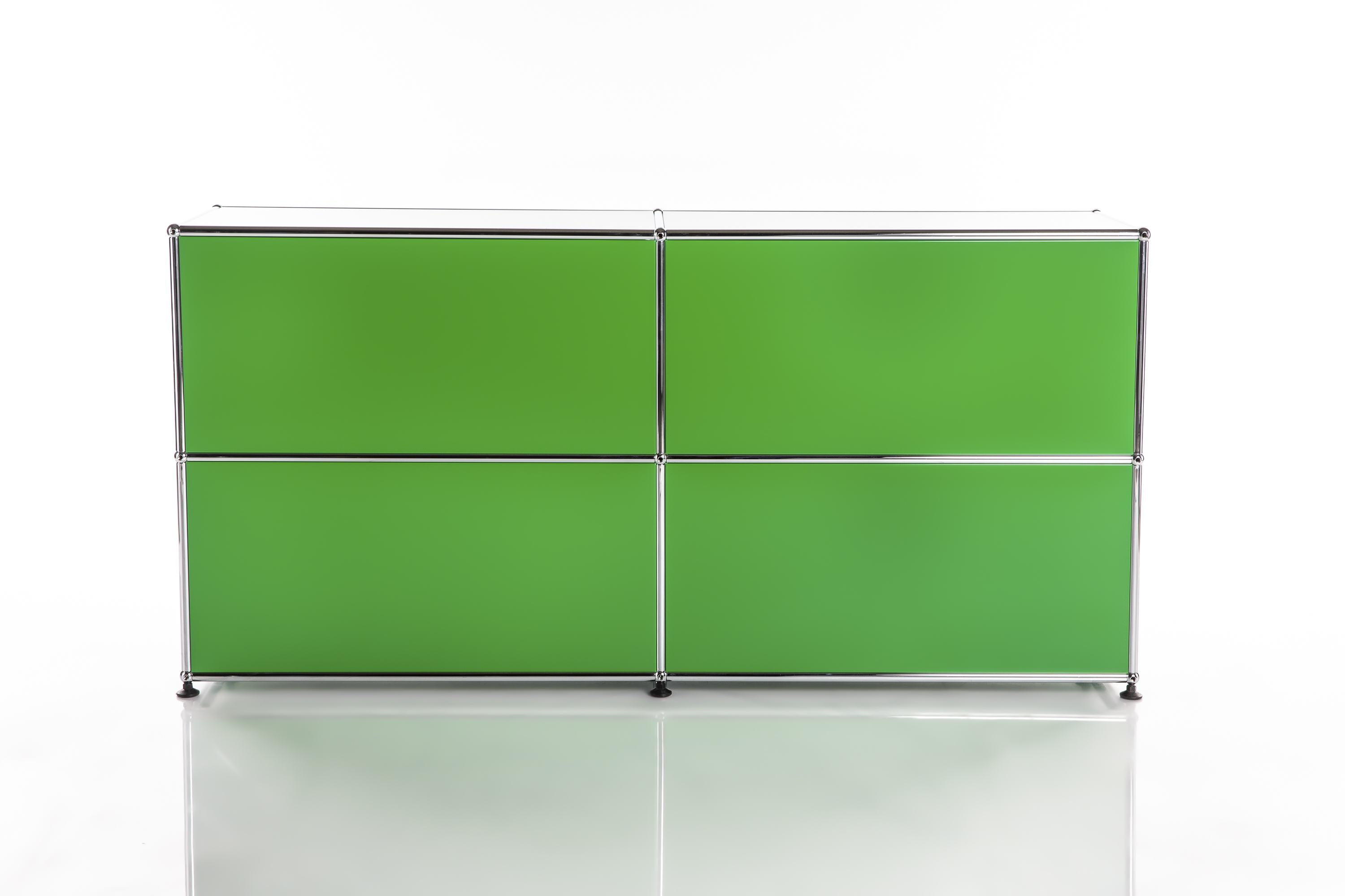 A modern, modular sideboard in a bold shade of green with four rectangular compartments and shiny chrome frames. Set against a light, reflective surface on a white background, it appears to float and emphasises its clean lines.
