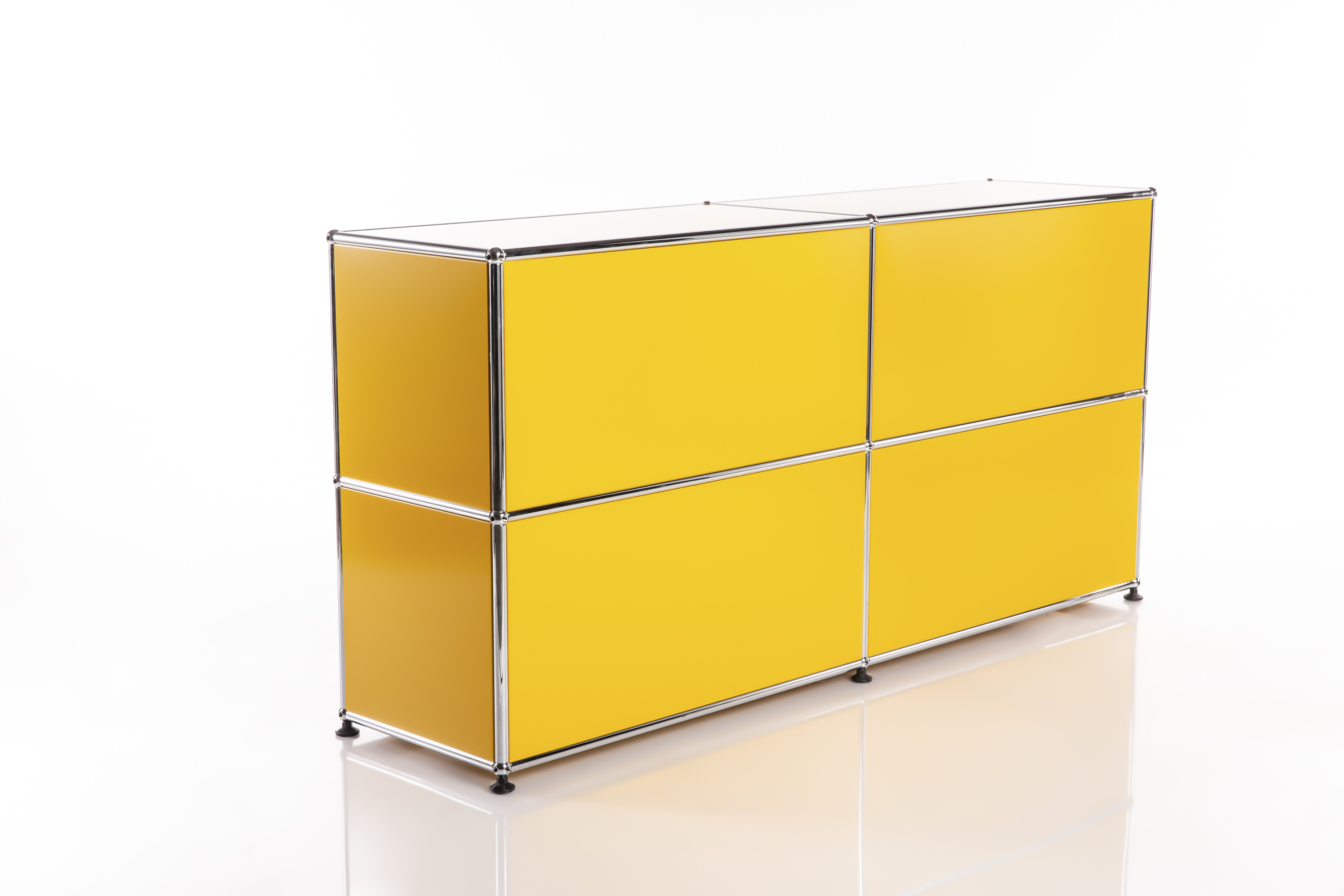Credenza modulare di un giallo brillante, con quattro scomparti quadrati disposti su due file e due colonne. I telai cromati lucidi uniscono gli elementi in una struttura lineare e moderna. Su piccoli piedini neri.