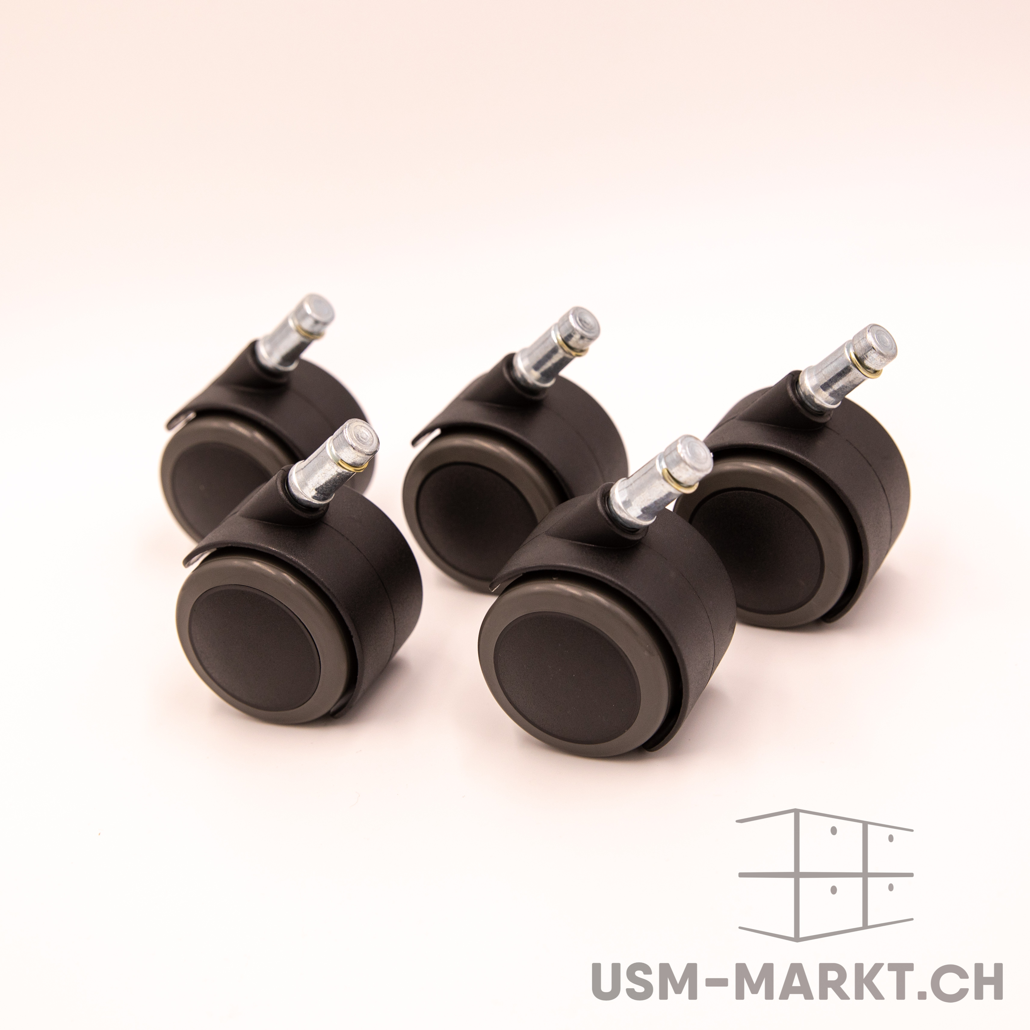 Cinque rotelle nere per sedie da ufficio su uno sfondo chiaro. Ogni rotella è dotata di un perno metallico argentato lucido per il fissaggio. Bicolori: grigio scuro all'esterno, nero all'interno, pronte per essere montate sulla base della sedia.
