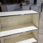Weißes USM Haller Regal mit drei offenen Fächern, leicht von vorne rechts fotografiert. Leere Ablagen und modulares System im Originalzustand, mit sichtbaren Gebrauchsspuren an weißen Flächen und Metallrahmen.