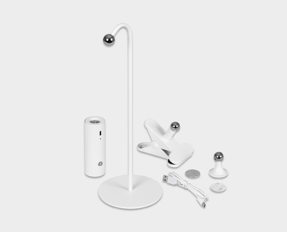 Einzelteile der Hansa Flare Spot LED-Tischleuchte auf hellem Grund. Sichtbar: Lampenfuß mit magnetischem Kugelkopf, Leuchtenkopf, Klemme, Wandhalterung, Metallplatte und USB-C Ladekabel.