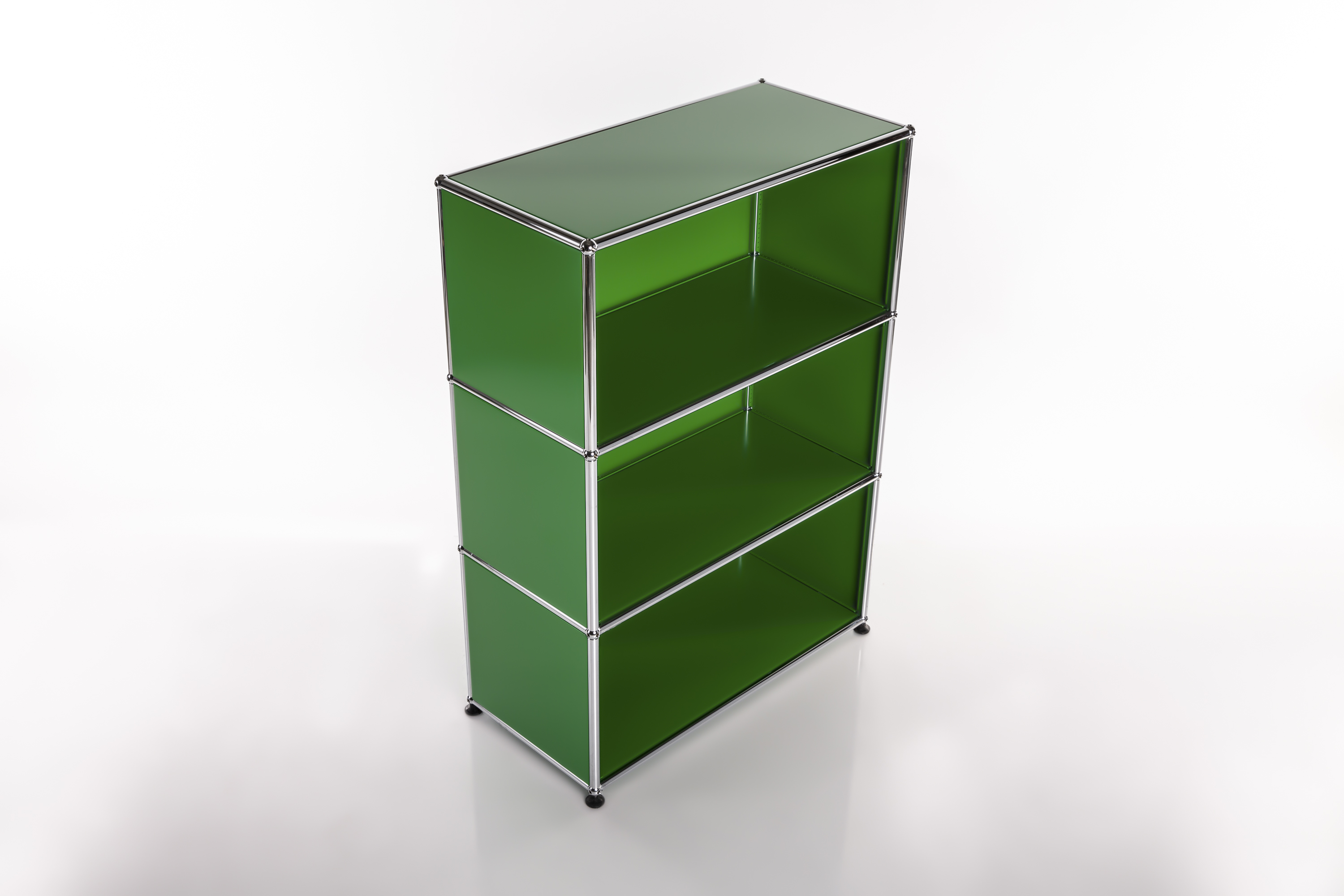 A three-tier, open-plan shelving unit crafted from glossy dark-green panels with a slender silver metal frame set against a light-coloured background. Three open compartments, small dark feet, a faint shadow on a white floor.