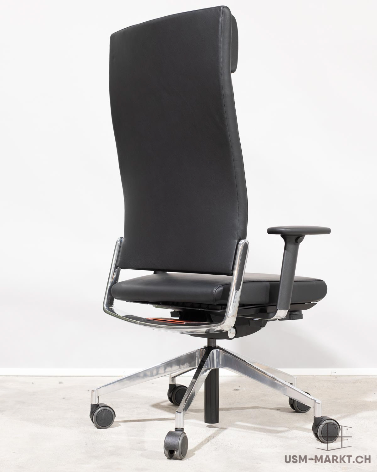 Chaise de bureau moderne noire à dossier haut, en cuir/similicuir, vue de dos à droite. Structure chromée, accoudoirs noirs et piètement à cinq branches argenté avec roulettes maniables. Élégante et fonctionnelle.