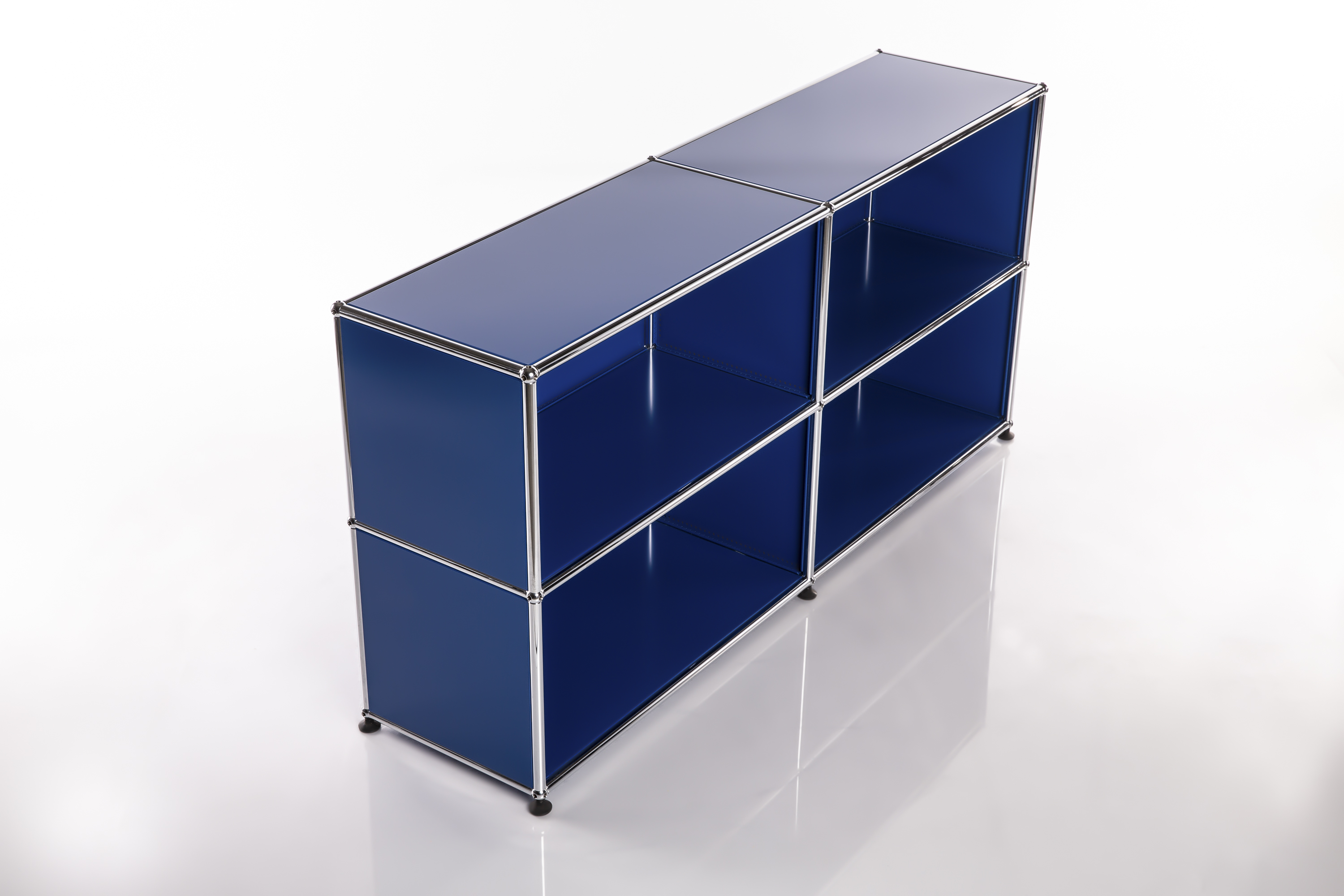 Étagère modulaire élégante avec quatre compartiments rectangulaires bleu foncé brillant. Cadre en tubes métalliques chromés et boules de liaison, posée sur petits pieds noirs. Reflets sur surface claire, fond blanc.