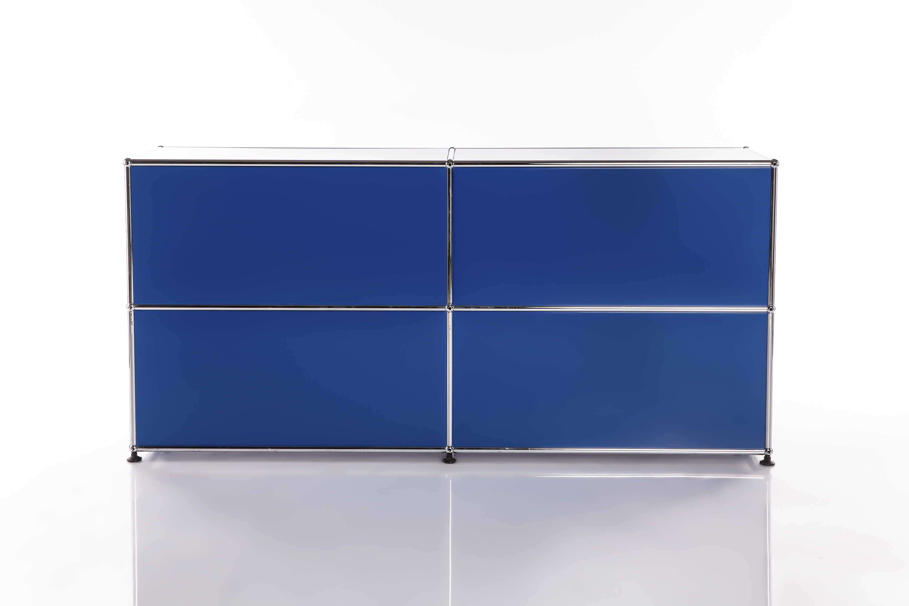 Système d'étagères modulaire moderne avec 4 panneaux frontaux bleu roi en grille 2x2. Structure en tubes métalliques argentés brillants et raccords sphériques. Pieds foncés, reflet sur sol clair, fond blanc.