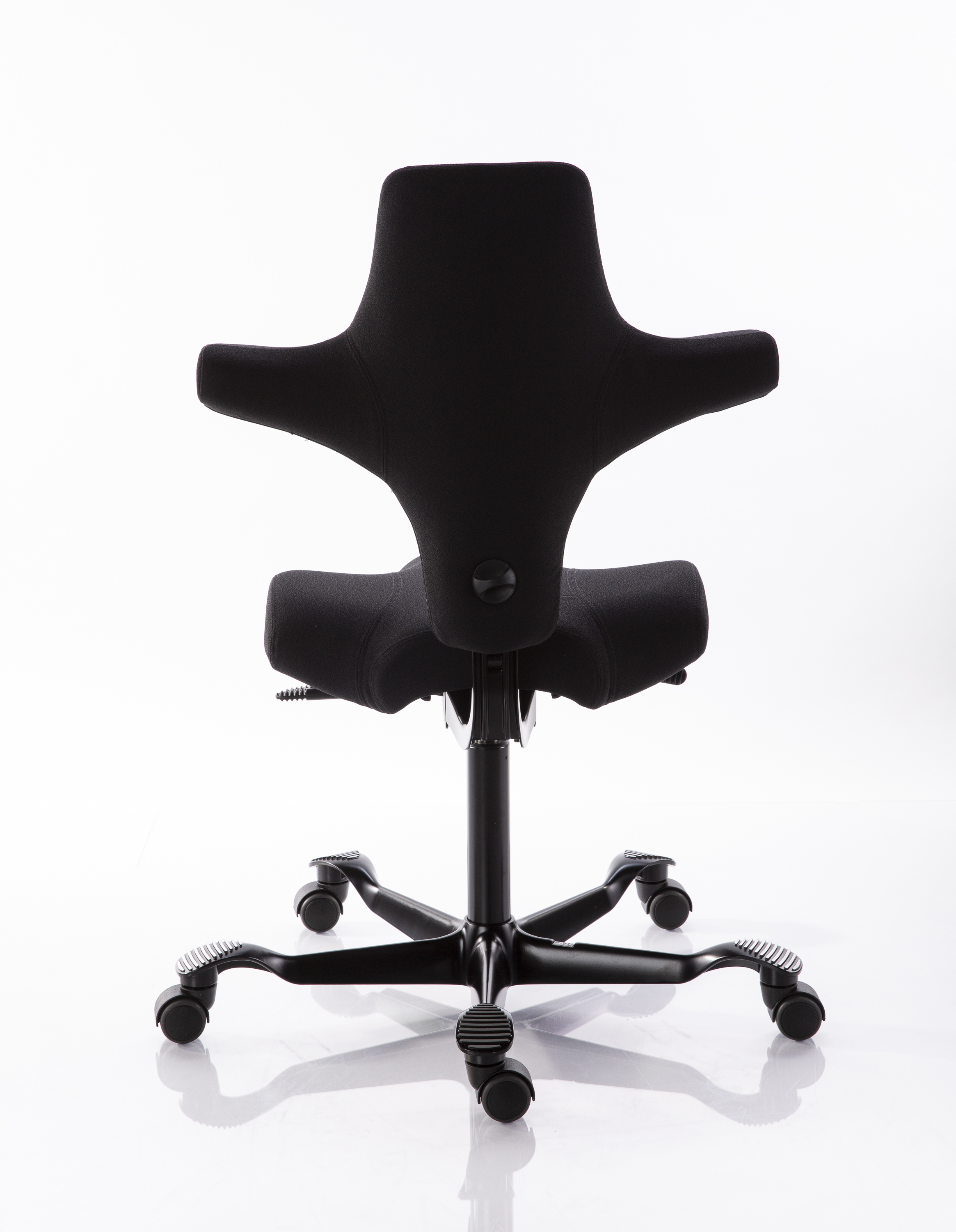 Chaise de bureau ergonomique noire vue de dos, dossier profilé plus large en haut avec renforts latéraux. Assise séparée ergonomique. Piètement à cinq branches foncé, avec roulettes et repose-pieds brillants.