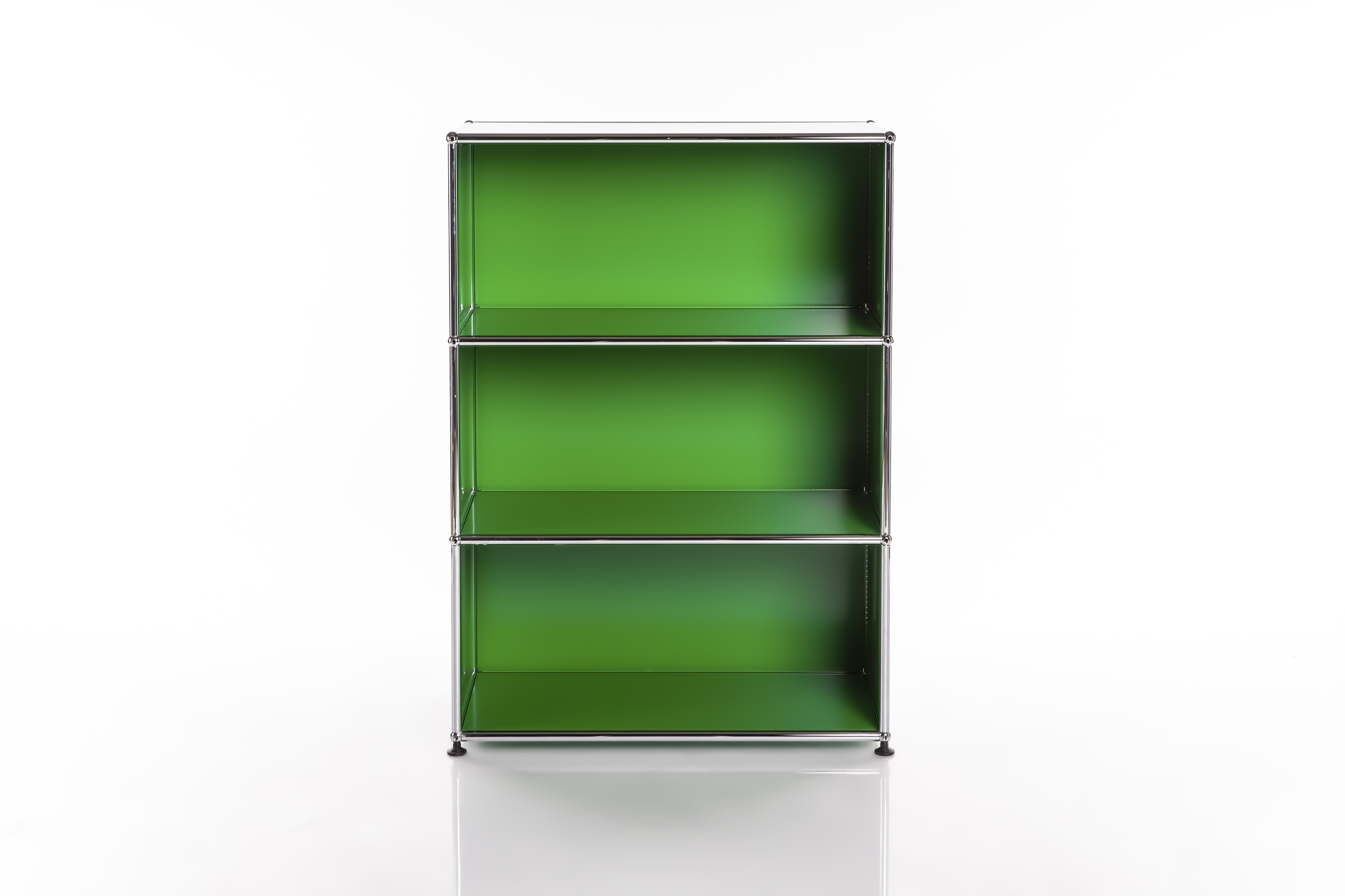 A modern green modular shelving unit with three open, vertically arranged compartments. Shiny chrome-plated frames enclose bright green interior panels. Stands on small black feet; the white surface has a slight sheen.
