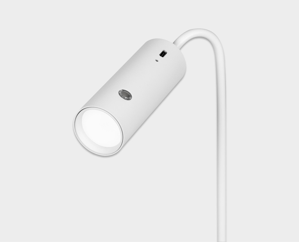 Schlanke, weiße Hansa Flare Spot LED-Tischleuchte im minimalistischen Design. Zylindrischer Leuchtenkopf mit hellem, neutralweißem Licht und rundem Bedienknopf seitlich. Dünner, gebogener Arm, tragbar und kabellos.