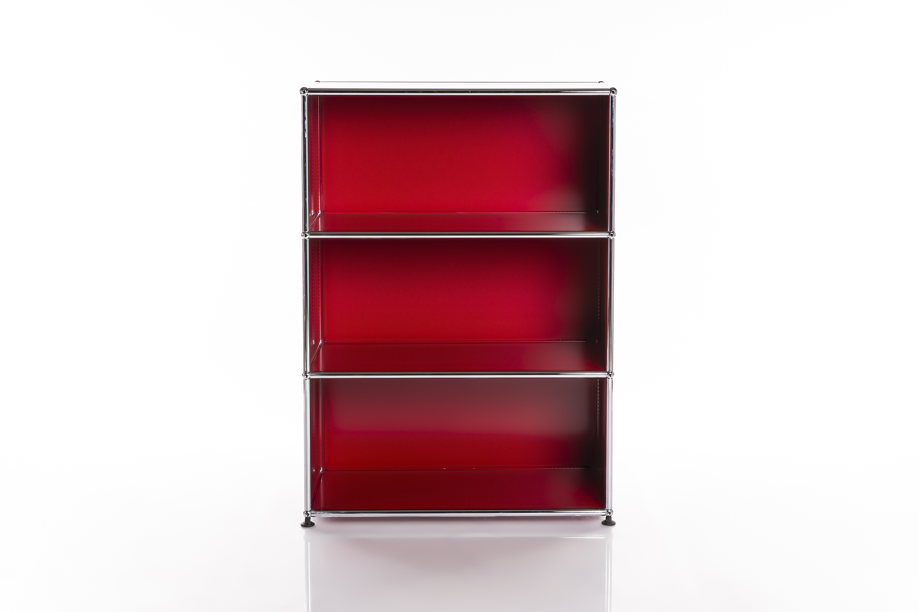 A sleek, three-tier modular shelving unit with bright red shelves set within a polished chrome frame. It stands on a reflective white surface against a pure white background, emphasising its minimalist, modern style.