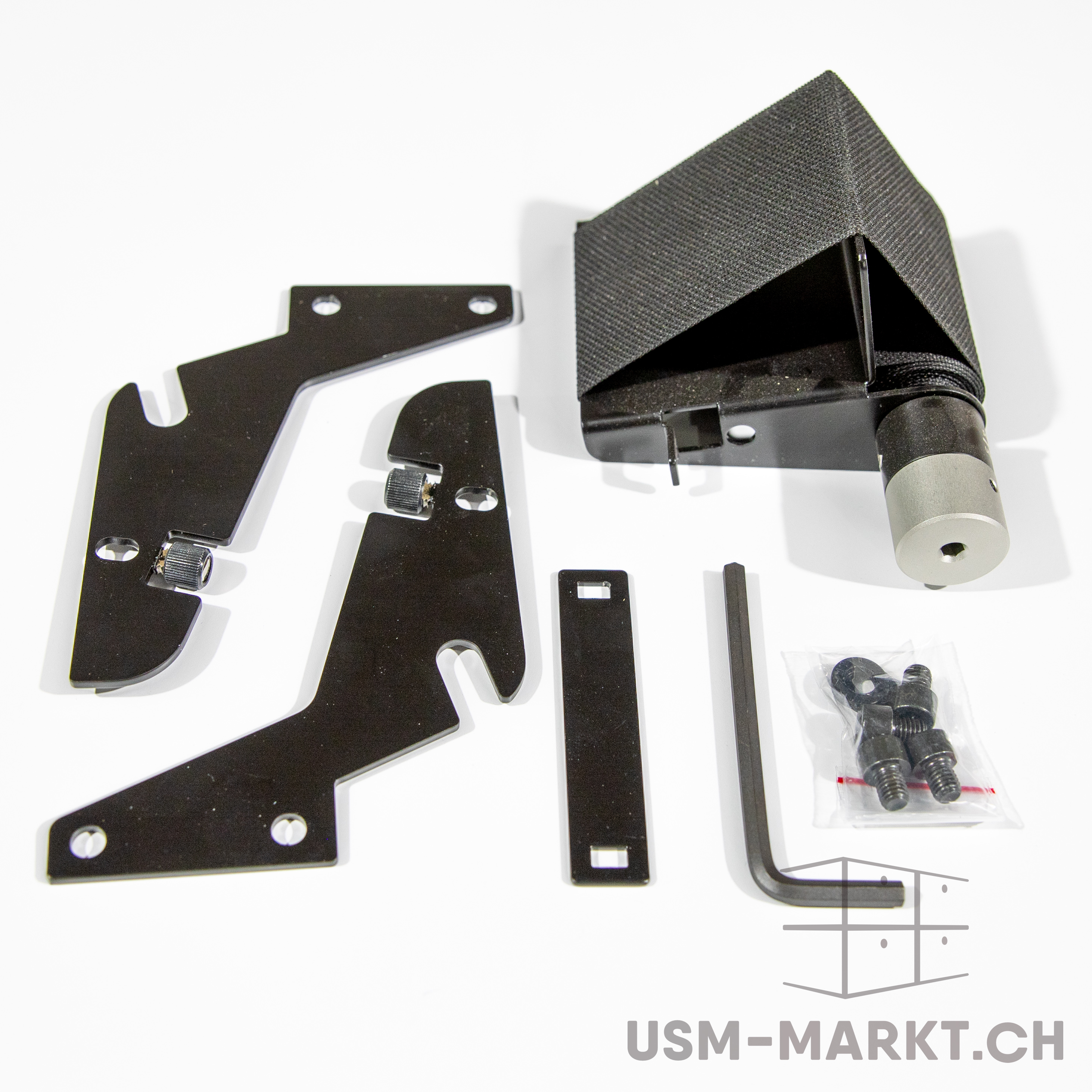 Set aus schwarzen Metallkomponenten und Befestigungselementen: winkelförmiges Gehäuse mit Zylinderkopf, zwei flache Montagewinkel, Verbindungsstück, Inbusschlüssel und Schraubenbeutel, auf weissem Hintergrund.