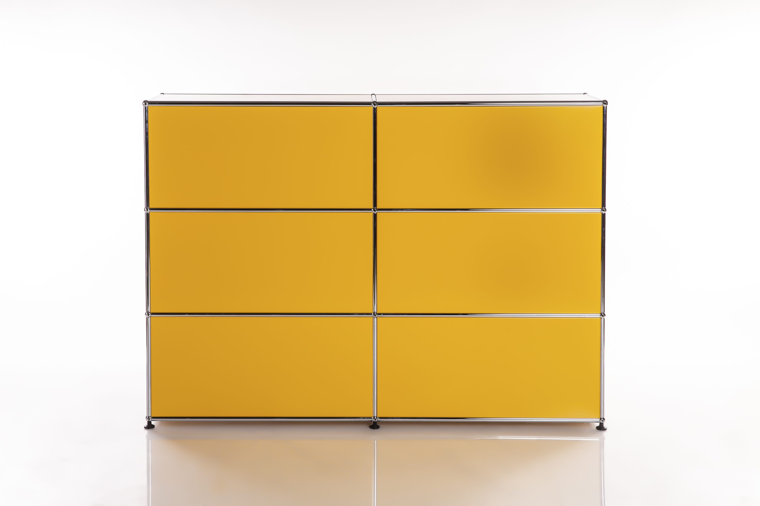 Buffet modulaire moderne d'un jaune vif, au centre d'un fond blanc. Six compartiments rectangulaires disposés en grille 3x2, encadrés d'un cadre chromé brillant. Léger reflet en dessous.