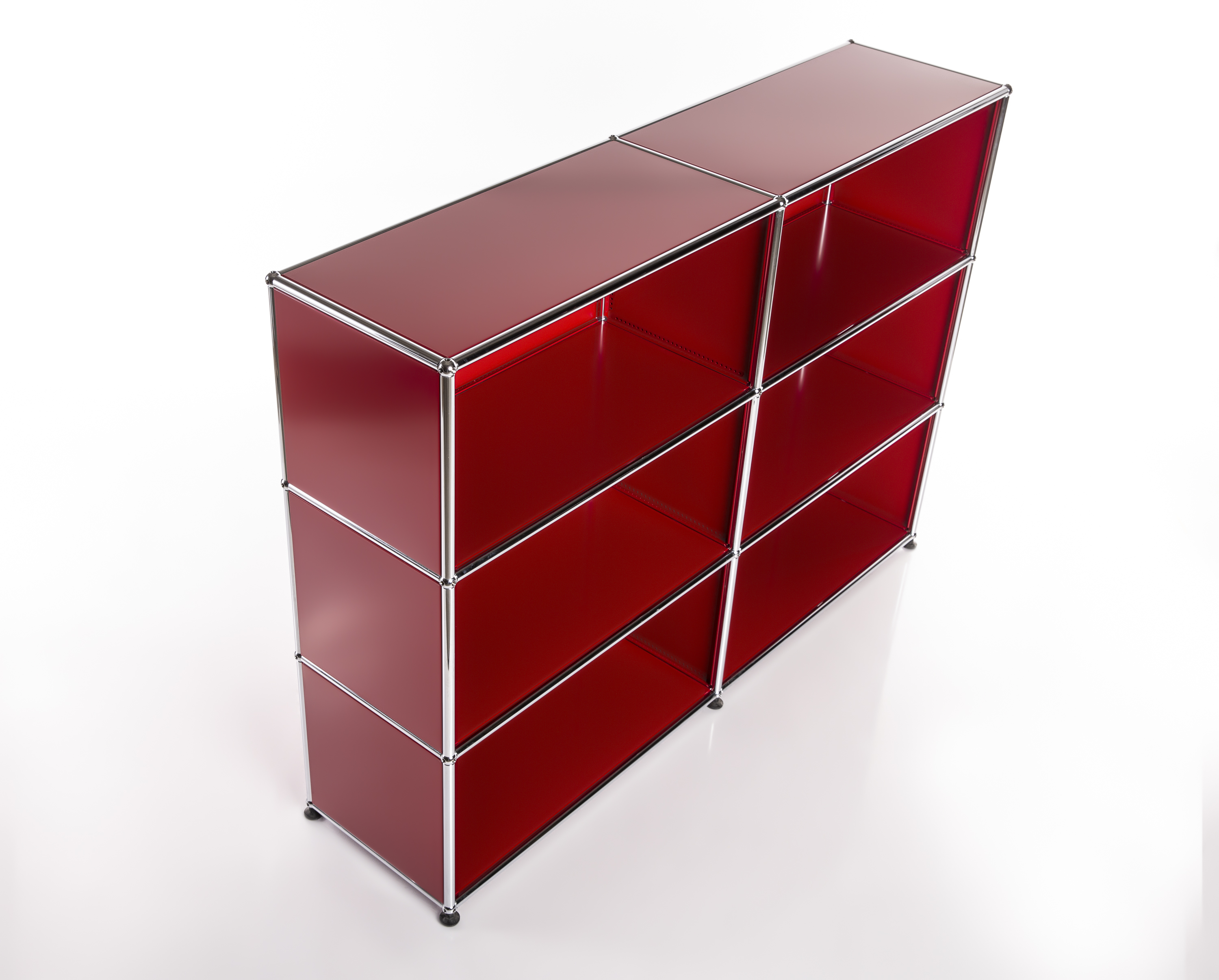 A glossy red, modern USM Haller shelving unit with six open compartments in three rows and two columns, against a minimalist white background. Modular design with red metal panels and chrome rods; surfaces slightly reflective.