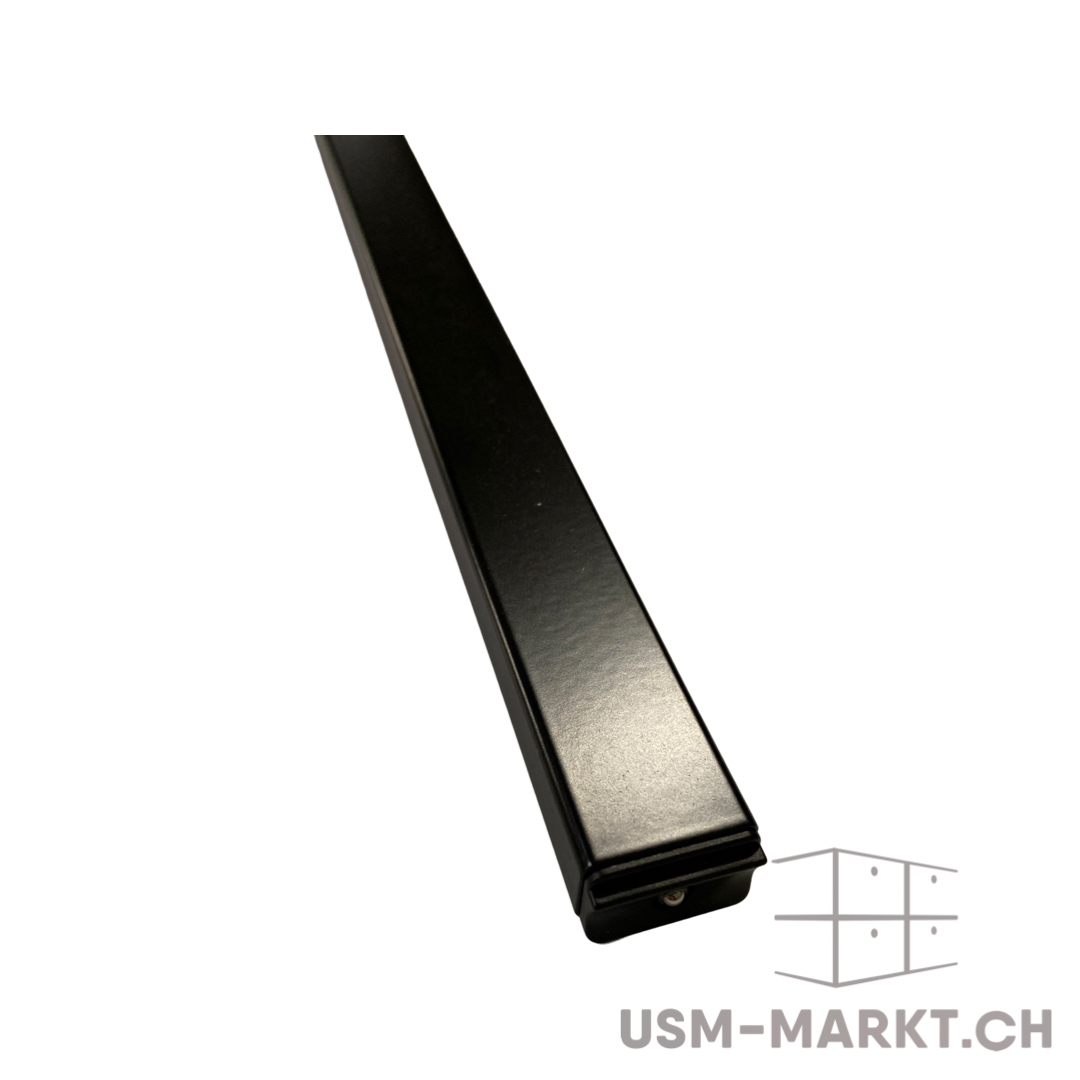 Schwarzes, mattes Metallprofil, diagonal von oben links nach unten rechts. Quadratischer Querschnitt, unten offen mit kleinem runden Loch. Reinweißer Hintergrund. Robust und minimalistisch, typisch für moderne Möbel oder Regalsysteme.