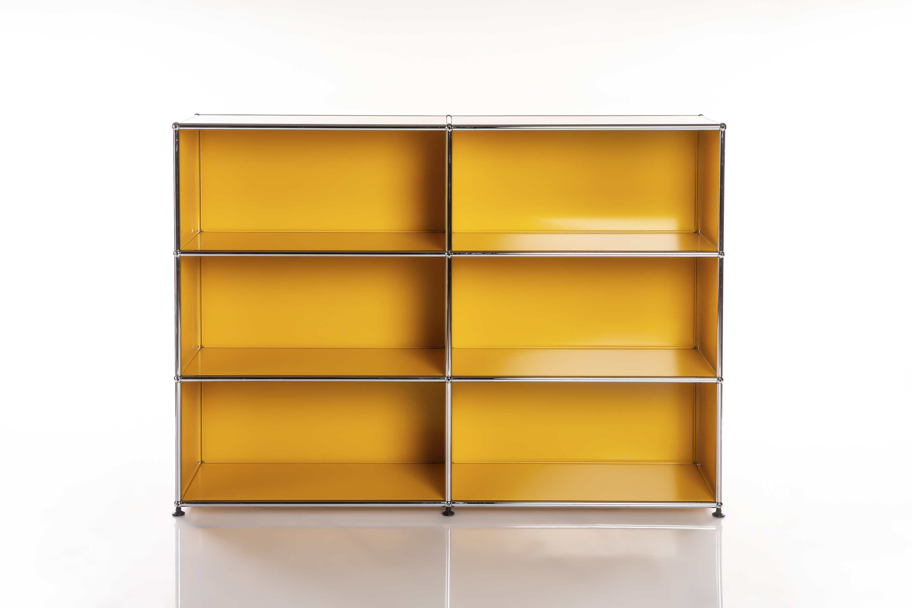 Une étagère moderne et modulaire composée de six compartiments ouverts d'un jaune vif. La structure est en chrome brillant. L'étagère est posée sur une surface blanche réfléchissante et disposée de manière symétrique devant un fond clair.