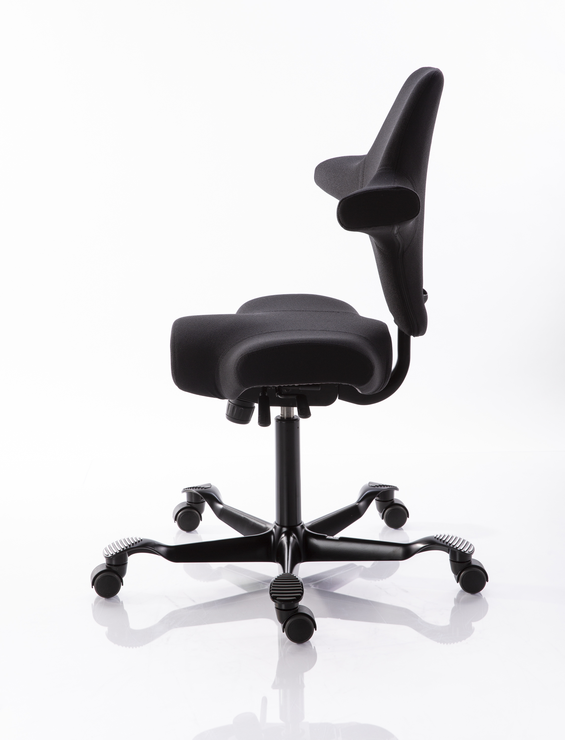 Une chaise de bureau ergonomique noire dotée d'une assise en forme de selle et d'un dossier qui soutient le bas du dos. La chaise est équipée d'un piètement à cinq branches et d'un vérin à gaz pour le réglage en hauteur, sur un socle lisse et blanc.
